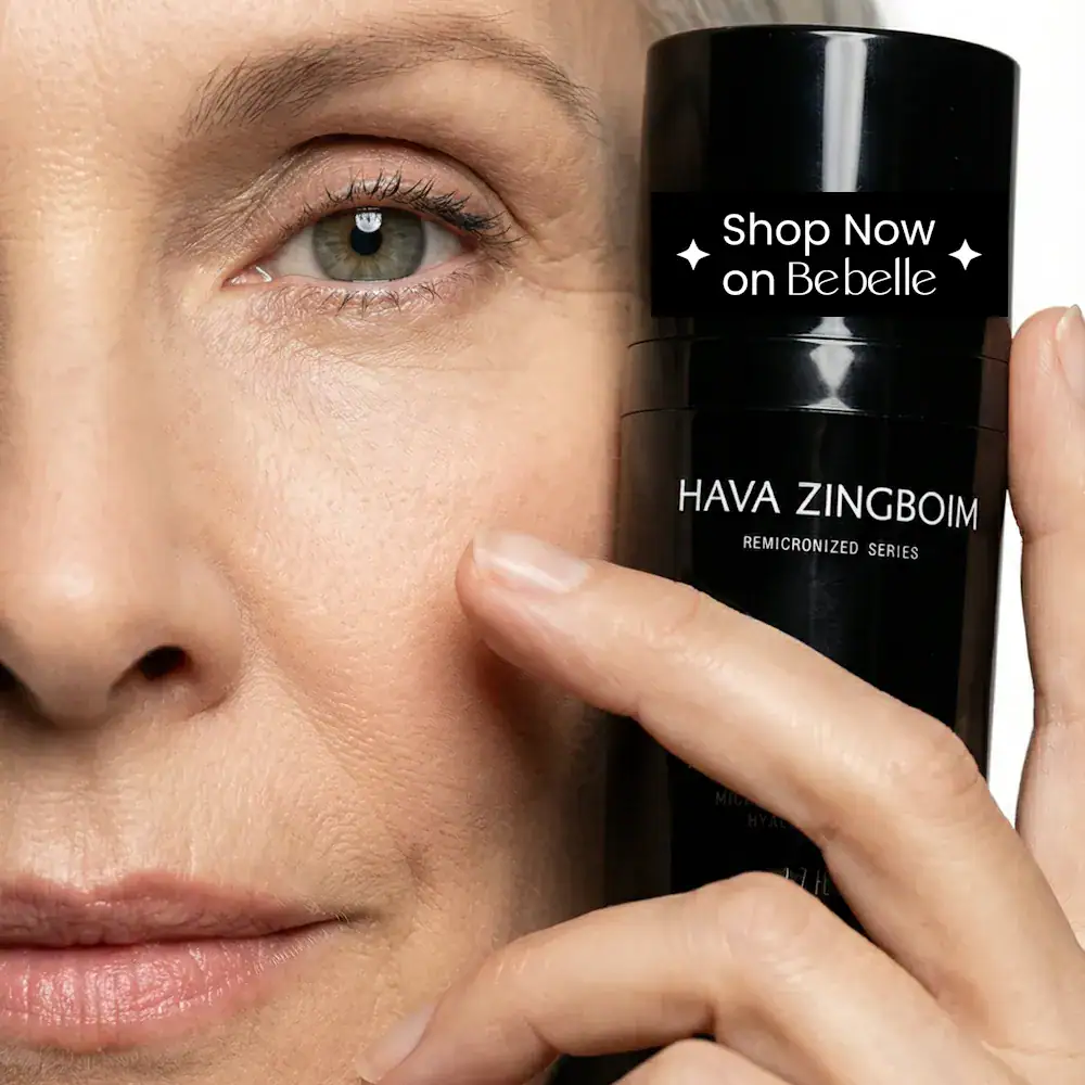 אישה מבוגרת נאה מחזיקה קרם עיניים רימייקרונייזד סמוך לפנים