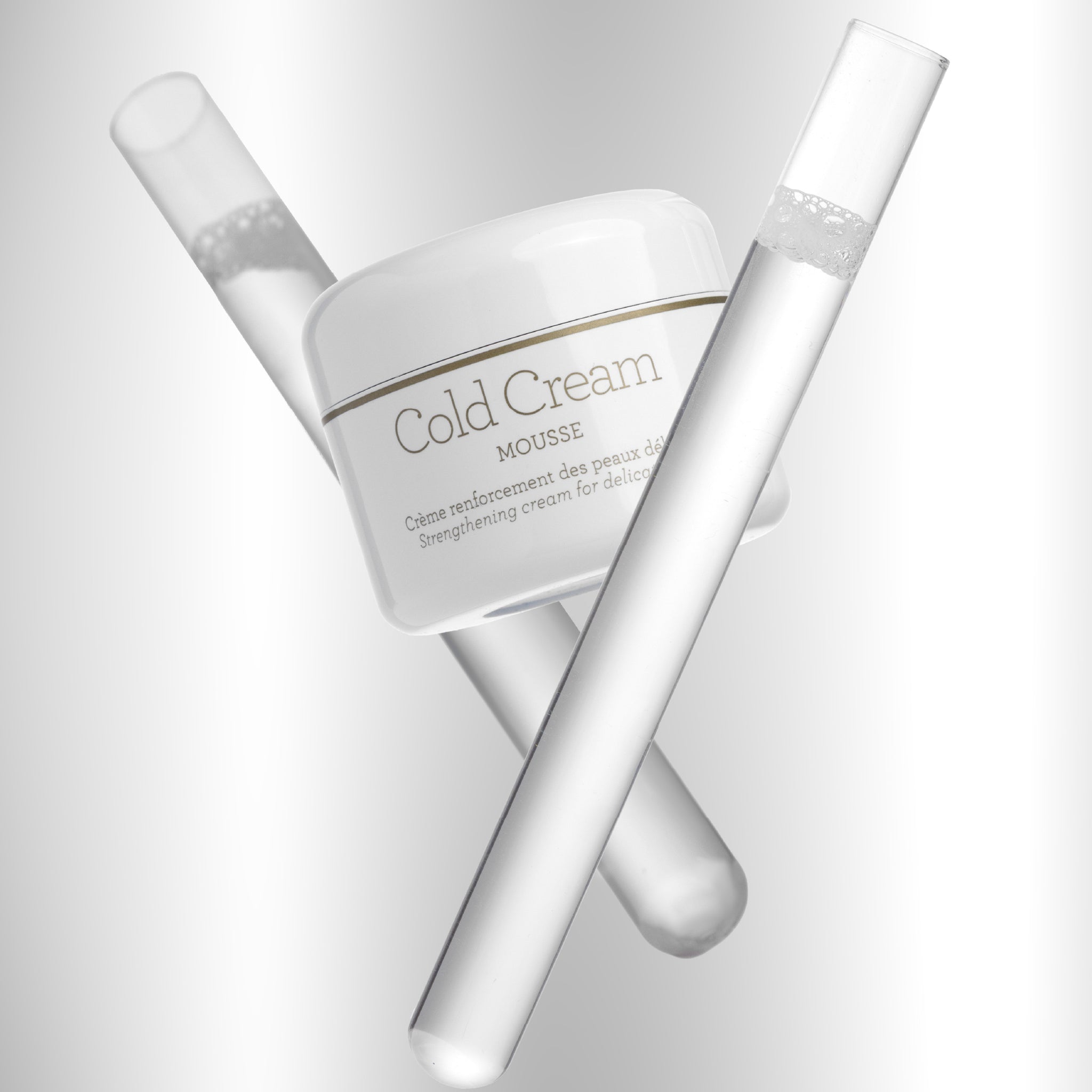 Cold Cream Mousse של GERnétic - צנצנת הקרם לצד כלי זכוכית מעבדתיים שקופים על רקע לבן