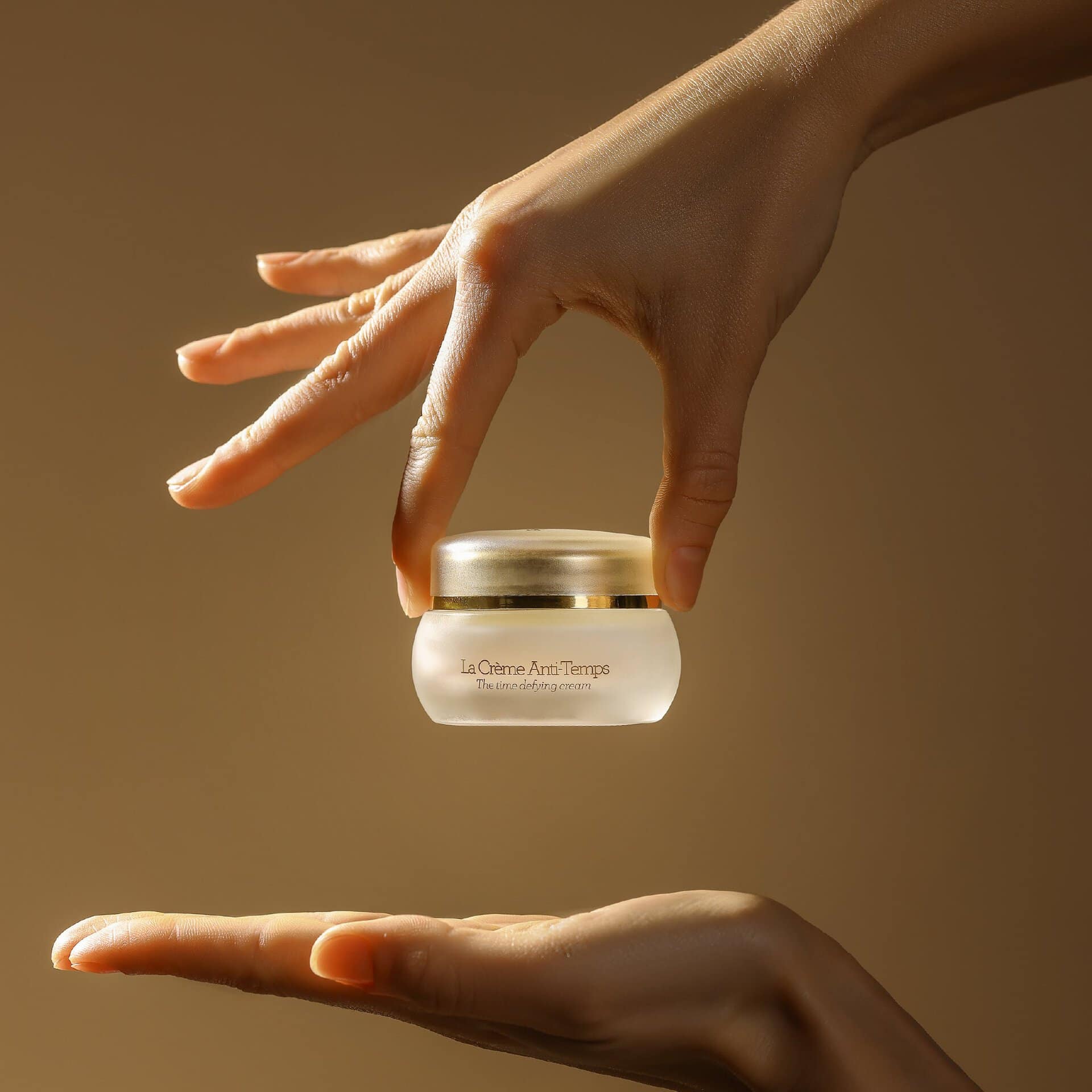 Crème Anti-Temps של GERnétic - צנצנת הקרם מוצגת בין שתי ידיים על רקע חם