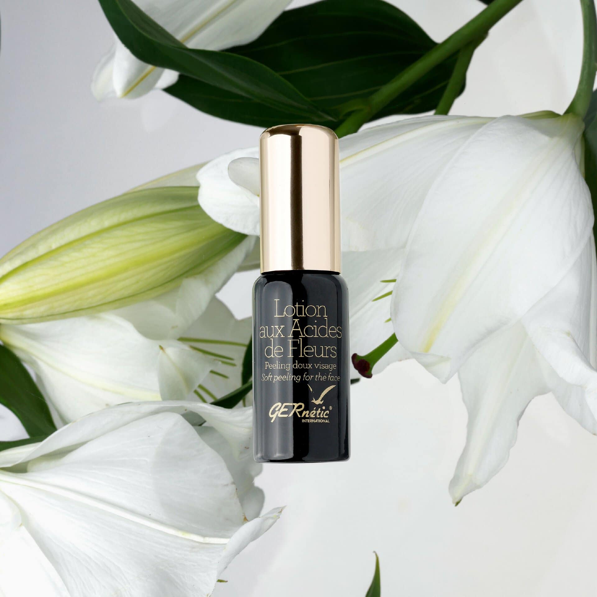 Lotion aux Acides de Fleurs של GERnétic - בקבוק התכשיר בין פרחי שושן לבנים ועלים ירוקים