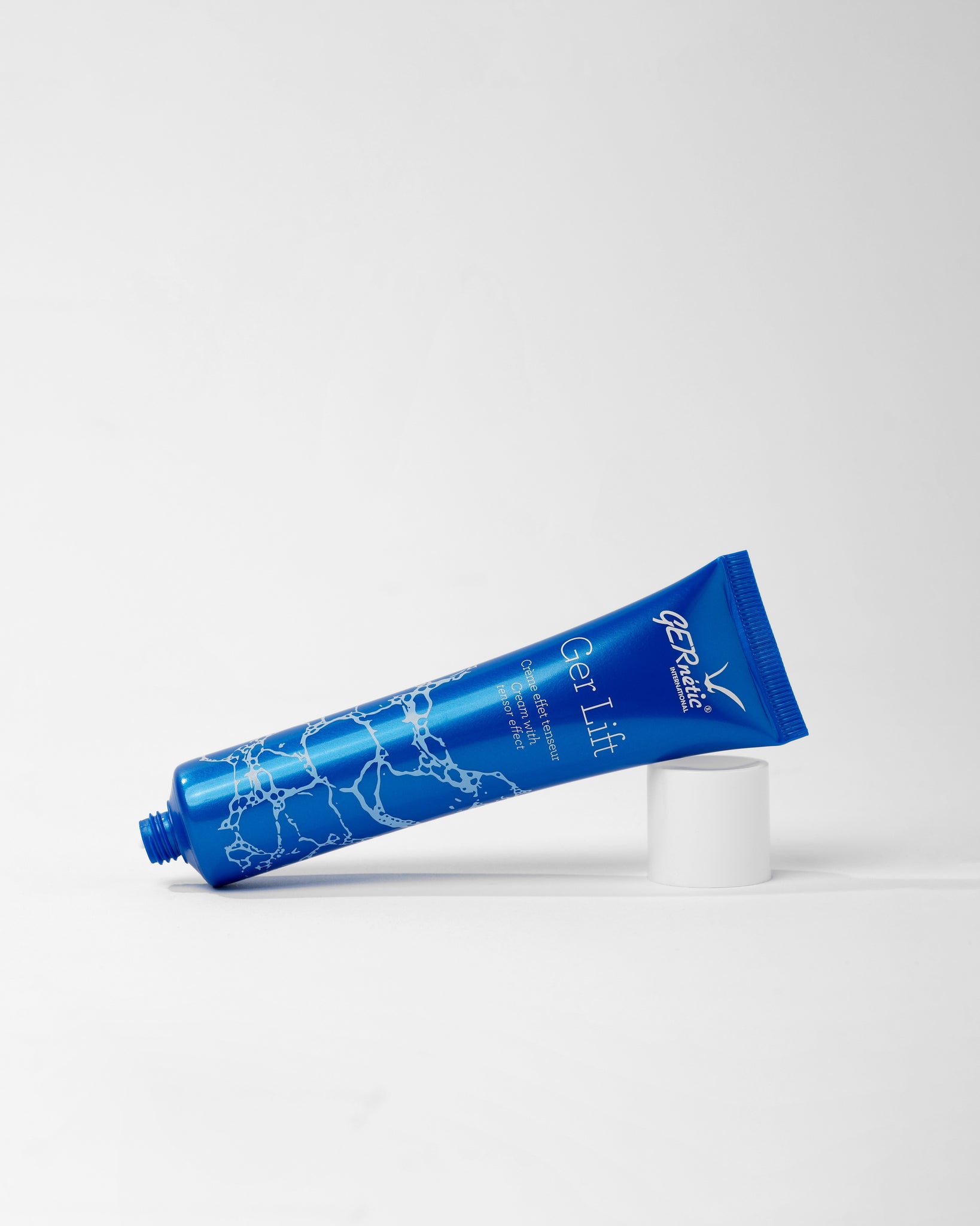 Ger Lift של GERnétic - שפופרת הקרם הכחולה פתוחה ומונחת באלכסון לצד הפקק הלבן