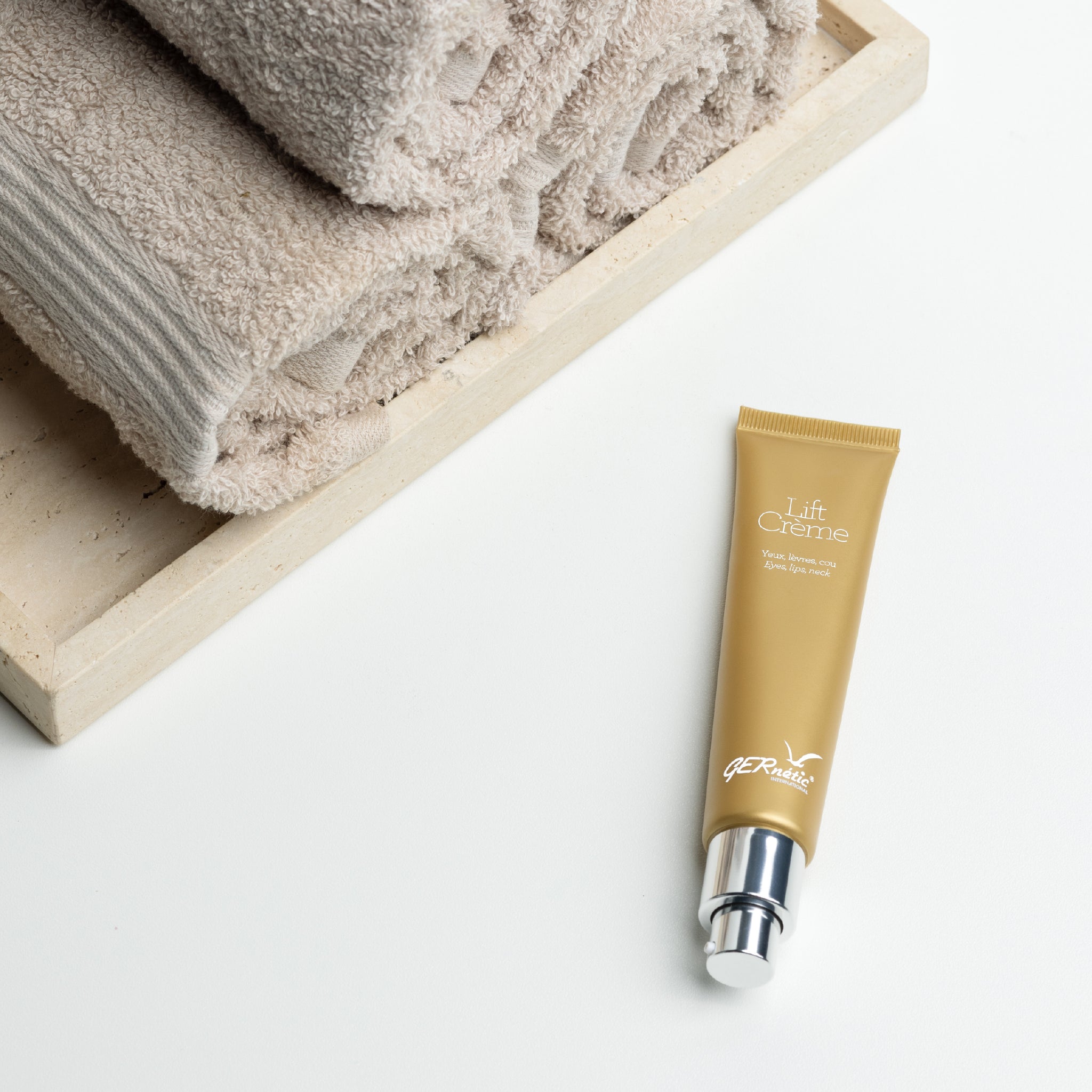 Lift Cream של GERnétic - שפופרת הקרם עם משאבה מונחת לצד מגבות מקופלות